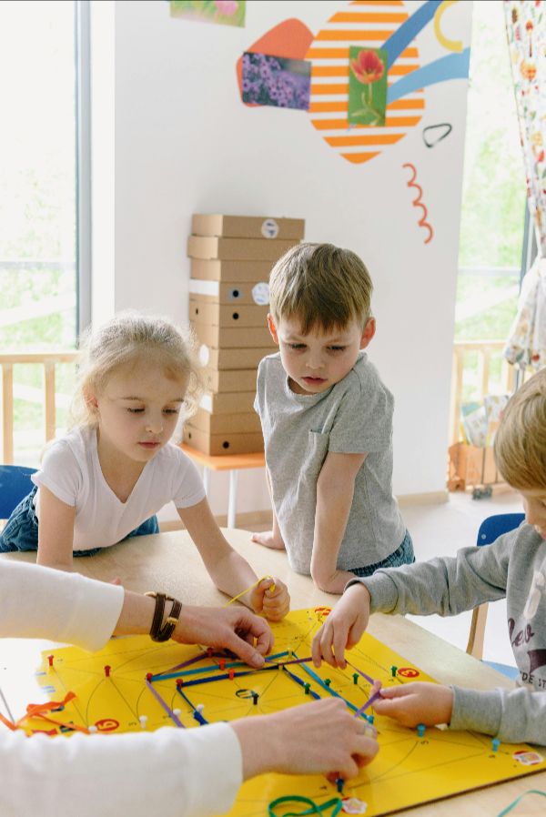 Caring teacher engaging with enthusiastic students in a colorful, nurturing classroom environment at Daily Bread Child Care Development Center