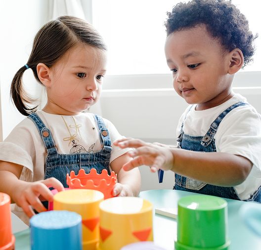 Group of toddlers collaboratively playing with colorful building blocks, developing fine motor skills and creativity at Daily Bread Child Care Development Center